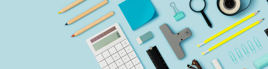 School supply, stationary flat lay on blue background. Banner size.