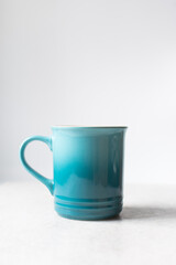 Ombre blue ceramic mug with white background and copy space, handmade gradient blue ceramic coffee cup on a white table