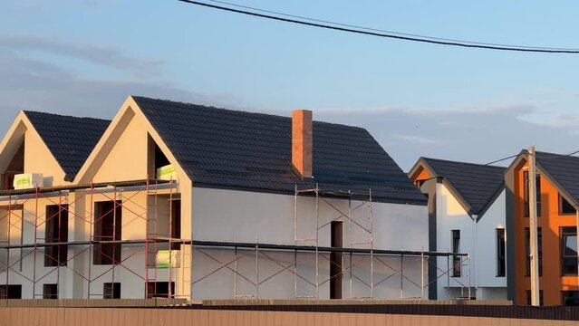 Duplexes under construction with scaffolding in the suburbs at summer sunset