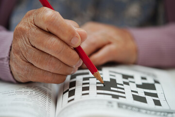 Asian elderly woman playing sudoku puzzle game to practice brain training for dementia prevention,...