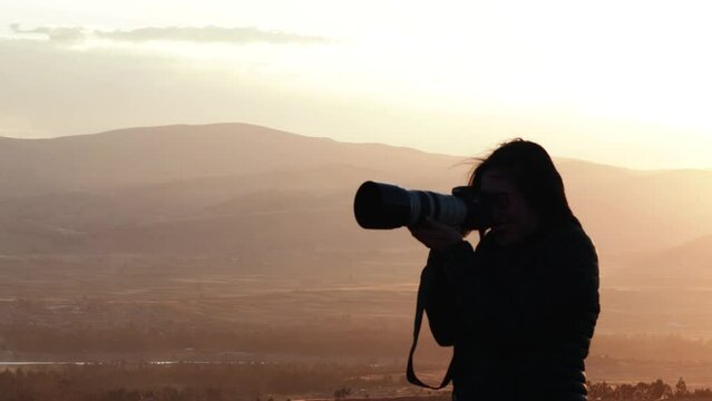 Video of a silhouette of a photographer at a sunset in the mountains. Concept of lifestyles, professions and nature.