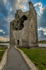 Partially demolished fortified tower house of Carrigafoyle castle in Ireland with dramatic sunset sky background