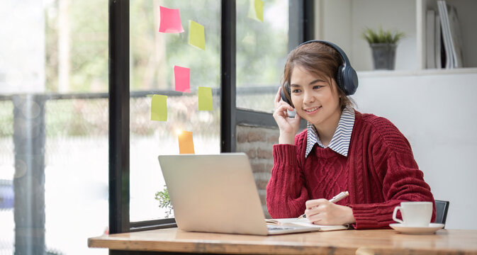 Asian female student study online in class, study online, wearing headphones, watching video call, zooming, happy asian female learning language online with computer laptop.