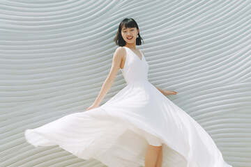 Fototapeta na wymiar Beautiful woman wearing flowing white dress and pose dancing over a light background. Generative AI.