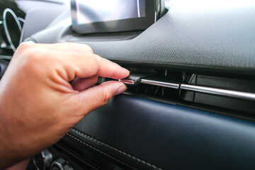 The driver hand adjusts the wind direction of the air vent in the car, button direction adjustment...