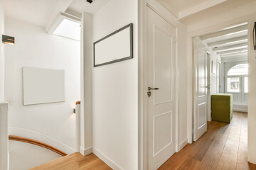 a hallway with white walls and wood flooring the room is well lit by natural light from the skylight