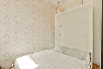 a bed in a room with wallpapered walls and a white headboard on the side of the bed