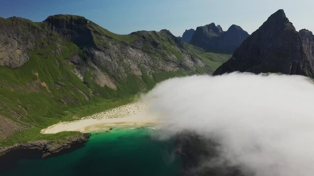 Cinematic revealing aerial shot of Horseid Beach with turquoise blue water, clouds moving over cliffs. Northern side of Moskenes&oslash;y, in the western part of Lofoten