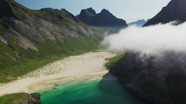 Cinematic aerial shot of Horseid Beach with turquoise blue water, clouds moving over cliffs, descending to isolated beach. Northern side of Moskenes&oslash;y, in the western part of Lofoten
