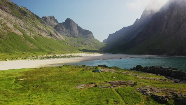 Revealing drone shot of Horseid Beach with turquoise blue water, clouds moving over cliffs. Northern side of Moskenes&oslash;y, in the western part of Lofoten