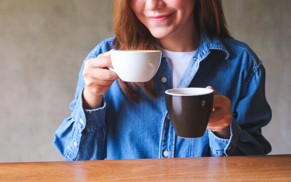 Closeup image of a beautiful young woman holding and drinking two cup of hot coffee