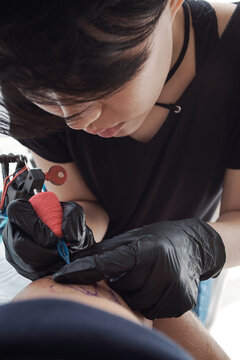 Female master making tattoo on arm