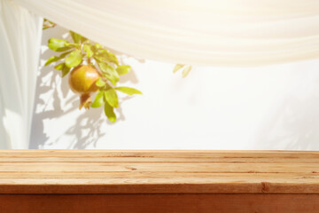 Jewish holiday Sukkot concept. Empty wooden table over pomegranate tree and sukkot background. Holiday mock up for design and product display