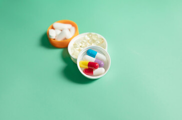 Pills in white bottle cap on green. Vitamins and healthy lifestyle. Background about health and medicine with copy space.