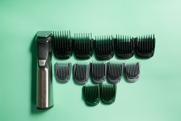 New metal wireless hair clipper, with set of attachments for different lengths green background. Styling beard, temples.