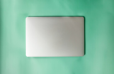 Modern laptop on green table, top view.
