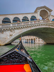 Fototapeta na wymiar Ponte di Rialto bridge in Venice, Italy. First person view from a traditional Venetian gondola, flat-bottomed Venetian rowing boat