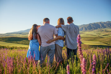 happy family in a field with flowers, mom, dad and children teenagers in nature