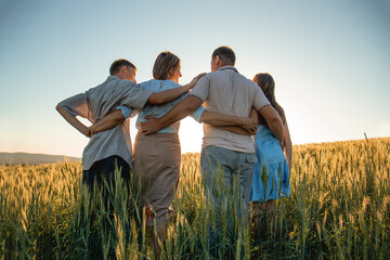 family of four in a field at sunset holding hands, happy family concept, children teenagers