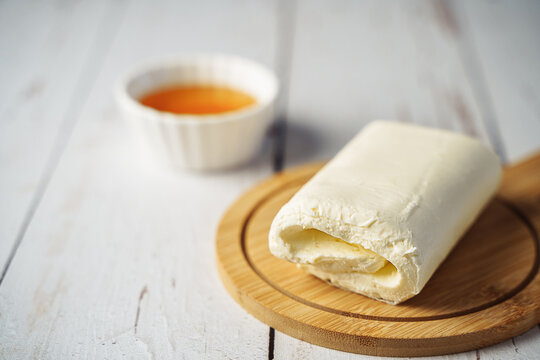 Close up picture of white cream milky kaymak butter roll poured with honey on wooden plate.