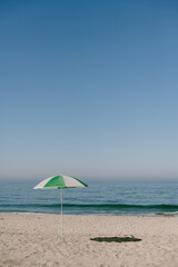 White and green umbrella on empty Carlsbad California beach