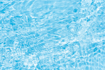 Blue water with ripples on the surface. Defocus blurred transparent blue colored clear calm water surface texture with splashes and bubbles. Water waves with shining pattern texture background.