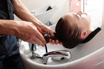 Hairdresser at work. Master hairdresser washes client's hair before doing her hair.A woman washes...