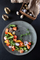 Red fish salad with radish and fresh cucumber. Lean dish. Healthy food. Dark background.Vertical photo.Top view.