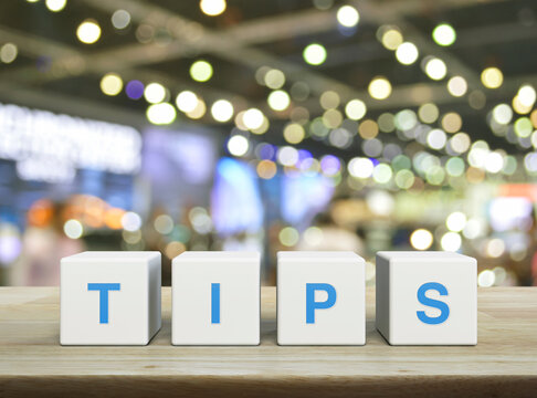 TIPS letter on white block cubes on wooden table over blur of shopping mall, Business customer service and support concept