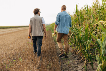 Back view of two farmers walking across the field.