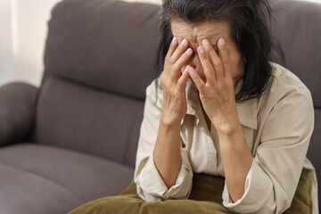 Sad middle age Asian woman touching forehead having headache suffering from migraine. mature asian woman feeling sick or depression.