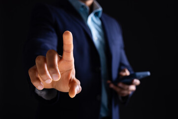 Biracial businessman holding smartphone and pointing on black background