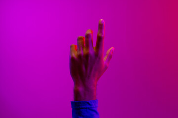 Hand of caucasian businessman pointing with copy space on neon pink to purple background