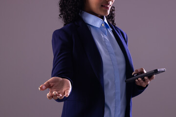 Biracial businesswoman using smartphone with copy space on grey background