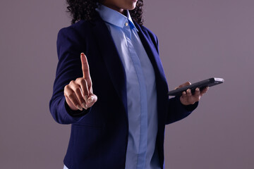 Biracial businesswoman using smartphone with copy space on grey background