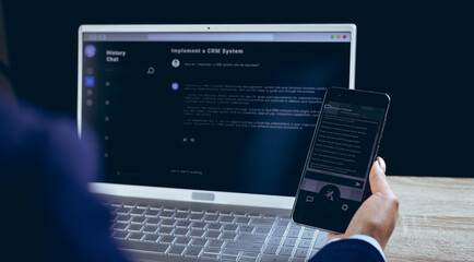 Biracial businesswoman using smartphone and laptop on black background