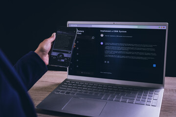 Biracial businesswoman using smartphone and laptop on black background