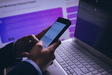 Biracial businesswoman using smartphone and laptop on black background