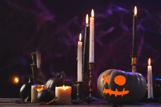 Fototapeta Carved pumpkins and burning candles on purple background
