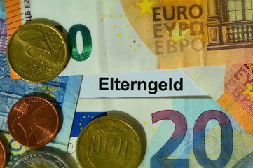 Das Wort Elterngeld mit Euro Geldscheinen und Münzen