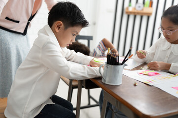 Asia kid boy studying with friend and teacher in classroom	