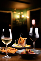 happy hour table in pub with two glasses of white and red wine and assorted portions of finger food