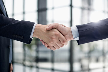 executives shaking hands in front of their manager and a colleague