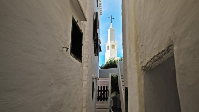 Binibeca Vell - a coastal village with narrow streets and whitewashed houses. White church tower on a summer sunny day in Menorca, Balearic Islands, Spain in 4k ProRes