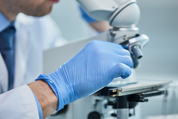 Scientist looks into a microscope near the laboratory, close-up