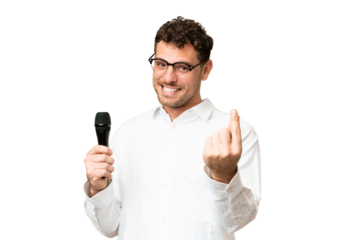 Brazilian man picking up a microphone over isolated chroma key background making money gesture