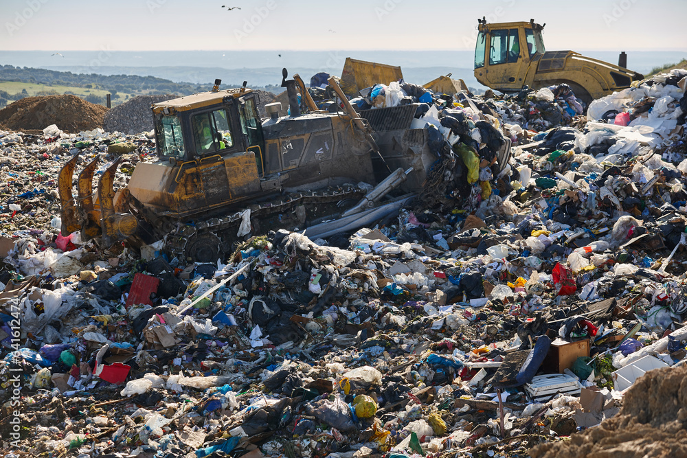 Wall mural Heavy machinery shredding garbage in an open air landfill. Pollution