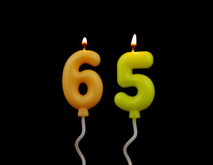 Air balloon shaped burning birthday candles isolated on black background, number 65.