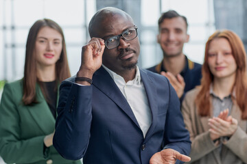 Successful trader. Modern young businessman in formal wear adjusting glasses looking at camera while standing in office