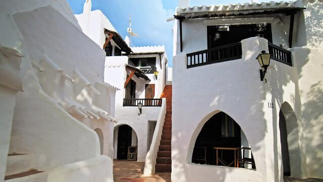 Narrow Whitewashed Streets in a tourist resort Binibeca Vell in Menorca, Spain. Beautiful small village town on the Balearic Islands with traditional brown wooden windows and doors in Europe.